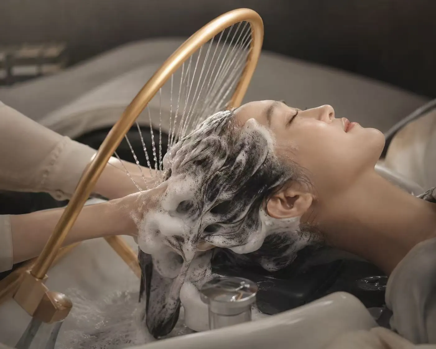 Warm water rinsing a lathered scalp under the gold halo ring, the head spa stage that opens every head spa and facial combo at Fiona's Day Spa in Coon Rapids, MN