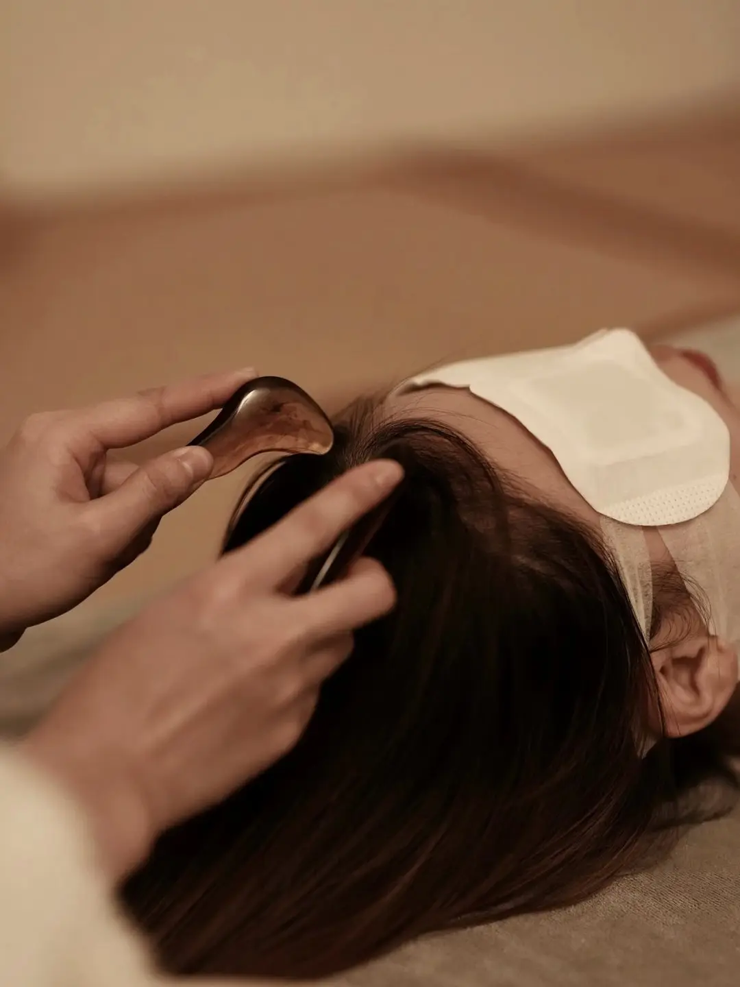 A gua sha tool drawn across the scalp during a head spa treatment booked from Blaine, MN